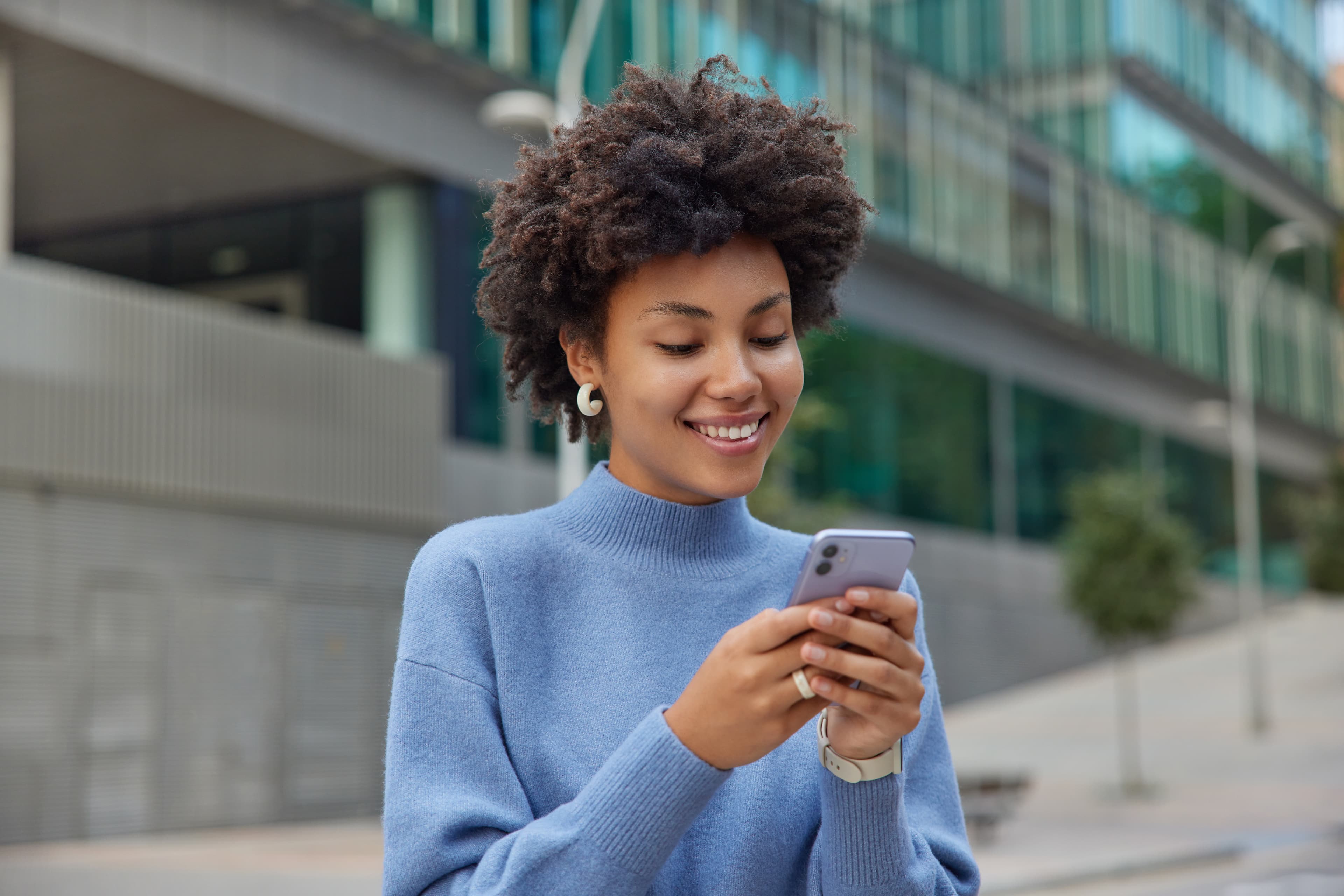 Mulher sorrindo ao olhar seu celular.